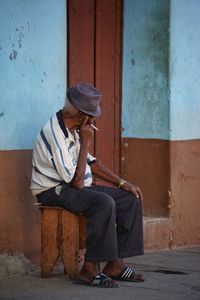 Man looking away while sitting on door