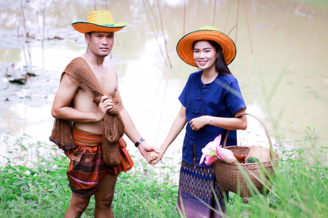 two people, three quarter length, real people, hat, standing, women, clothing, basket, togetherness, young adult, casual clothing, young women, bonding, adult, plant, people, front view, smiling, leisure activity, men, couple - relationship, hairstyle