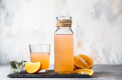 Orange lemonade in glass and bottle with fresh orange. refreshing summer drink.