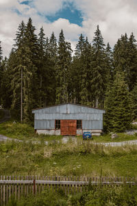 House amidst trees and plants growing on field against sky