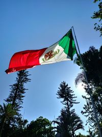 Low angle view of flags against clear blue sky