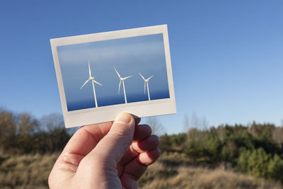 Hand holding photo of wind turbines