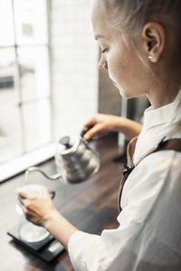 Side view of barista pouring boiling water in coffee filter