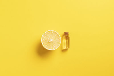 Serum with vitamin c. lemon essential oil. glass bottle with a pipette, lemon on yellow background