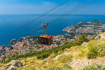 Overhead cable car over mountain against blue sky