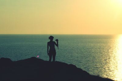 Silhouette men standing on shore against clear sky