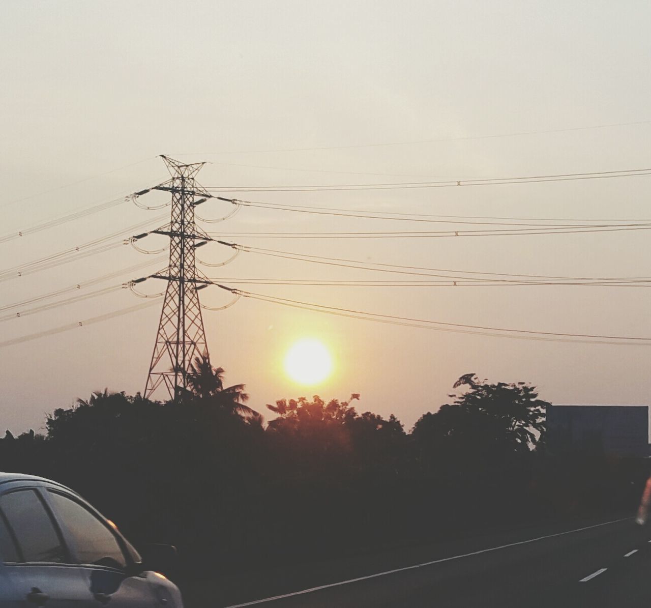 power line, sunset, electricity pylon, sun, transportation, electricity, silhouette, power supply, cable, car, clear sky, sky, tree, fuel and power generation, connection, sunlight, power cable, mode of transport, nature, sunbeam