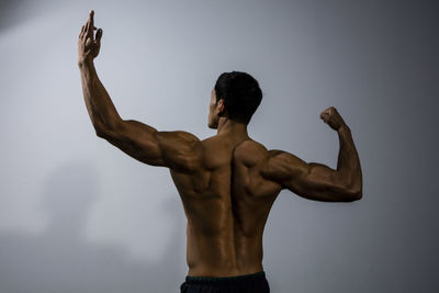 Shirtless muscular man standing against wall