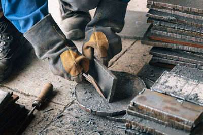 Worker in heavy industry or metallurgy beats scale off iron plates with hammer. work with metal