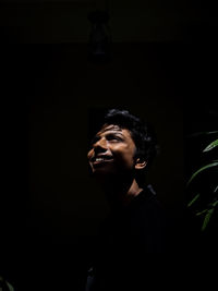 Young man looking away in dark background