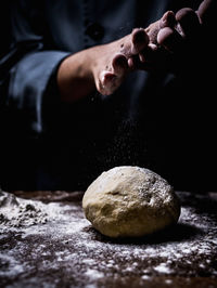 Midsection of person kneading dough in kitchen