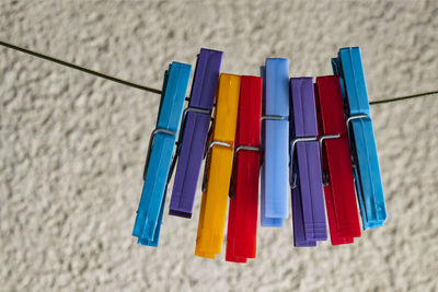 Close-up of multi colored clothespins on clothesline against wall