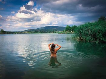 Woman in the water surrounded by green vegetation and dark storm clouds