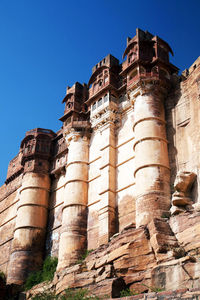 Low angle view of mehrangarh fort against clear blue sky