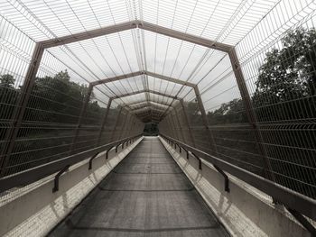 View of footbridge in greenhouse against sky