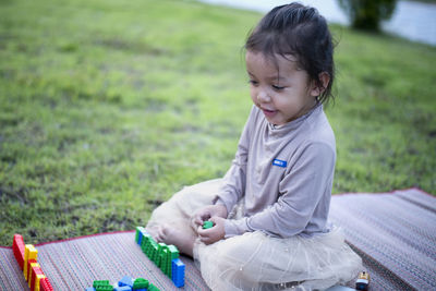 Side view of young woman sitting on field