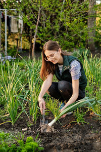 Woman works on the ground growing organic plants, fruits and vegetable