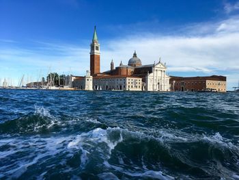 Scenic view of venetian lagoon by buildings against sky 