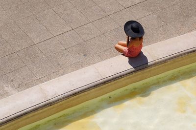 High angle view of woman sitting on wall by fountain