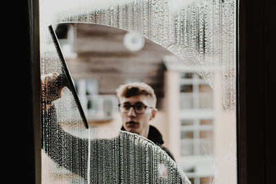 Portrait of man standing by window