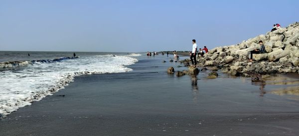 People on beach against clear sky