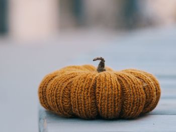 Knitted orange pumpkin on a wooden table.