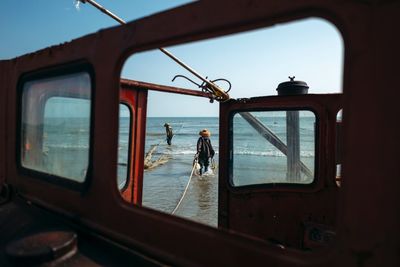 Reflection of man in boat on sea against sky