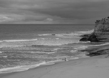 Scenic view of shore and sea against cloudy sky