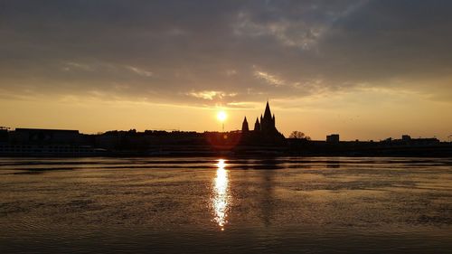 Silhouette of temple at riverbank during sunset