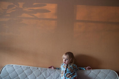 Girl against wall on sofa in living room at home