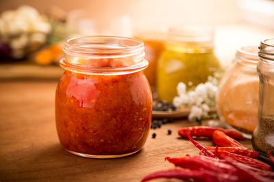 Close-up of red chili pepper paste in jar by spices on wooden table