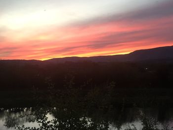 Scenic view of silhouette mountains against orange sky