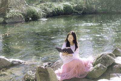 Side view of young woman sitting in lake