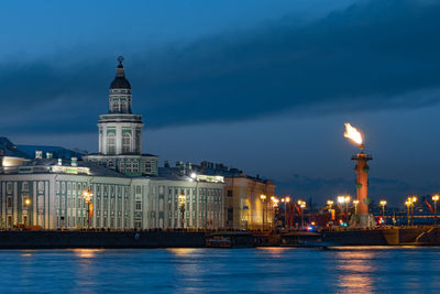 Illuminated buildings by river at night