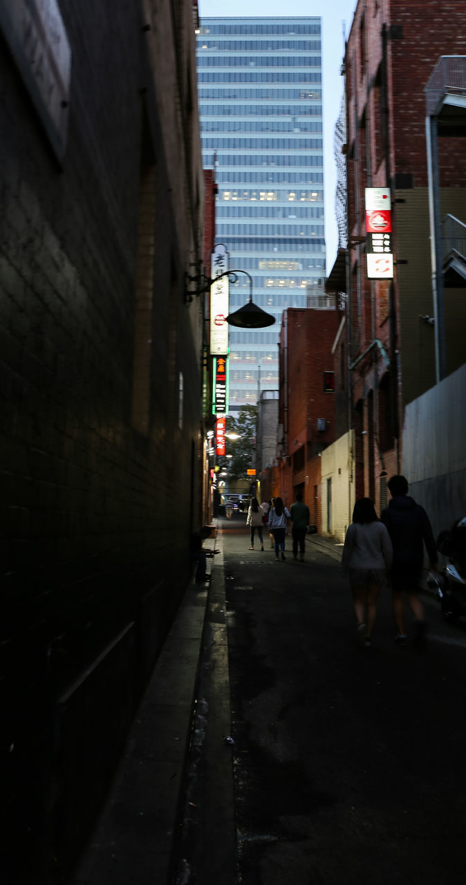 PEOPLE WALKING ON STREET AMIDST BUILDINGS