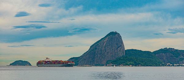 Photo of sugarloaf mountain with a cargo ship passing in front of it in guanabara bay