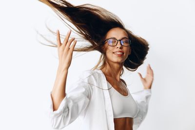 Portrait of young woman standing against white background