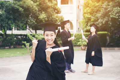 Cheerful student with clenched fist wearing graduation gown