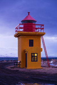 Orange lighthouse at the ocean in the evening, iceland