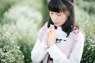 Woman praying while standing amidst plants