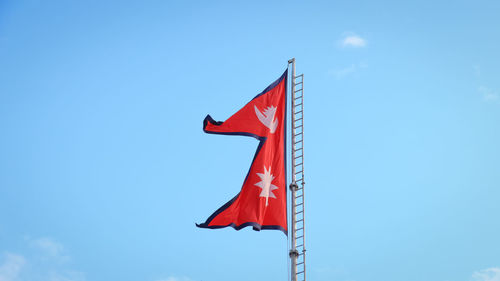 Low angle view of red flag against sky