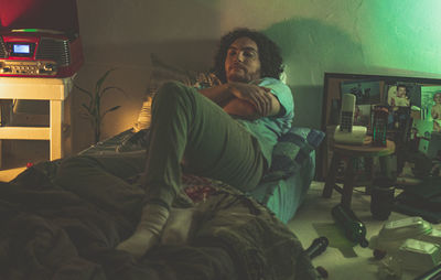 Young woman sitting on bed at home