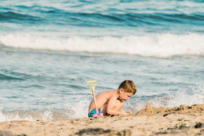 Rear view of shirtless boy on beach