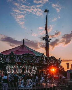 Low angle view of illuminated ferris wheel against sky at sunset
