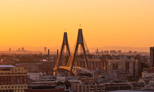 Sailboats in city against sky during sunset