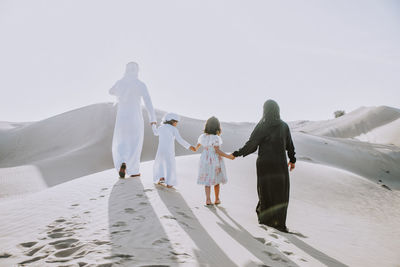 Rear view of family walking on sand dune