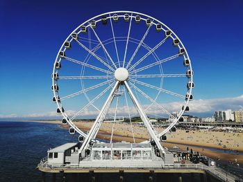 Ferris wheel in city against blue sky