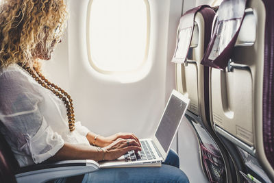 Side view of businesswoman using laptop at airplane