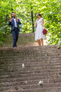 A wedding couple snapped in the action on the staircase in the nature surrounded by green trees