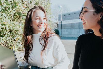 Smiling female friends walking together on sunny day